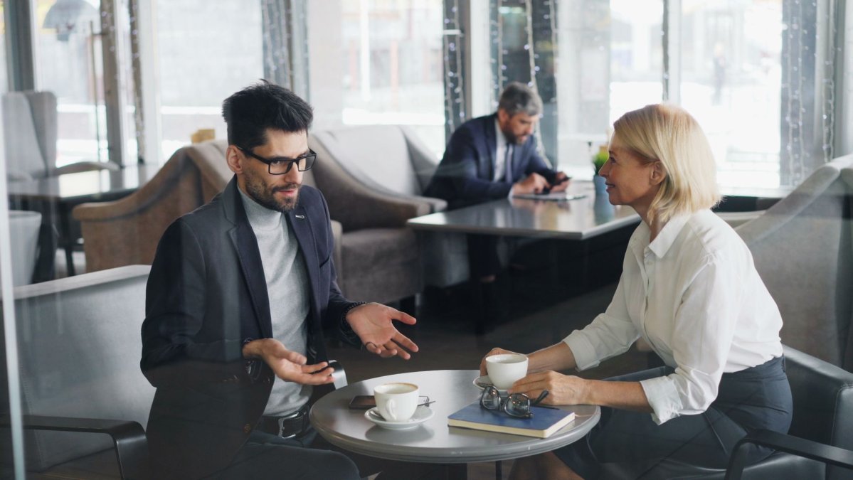 professional-colleagues-discuss-work-over-coffee-in-a-contemporary-cafe-setting-stock-1790948823-1